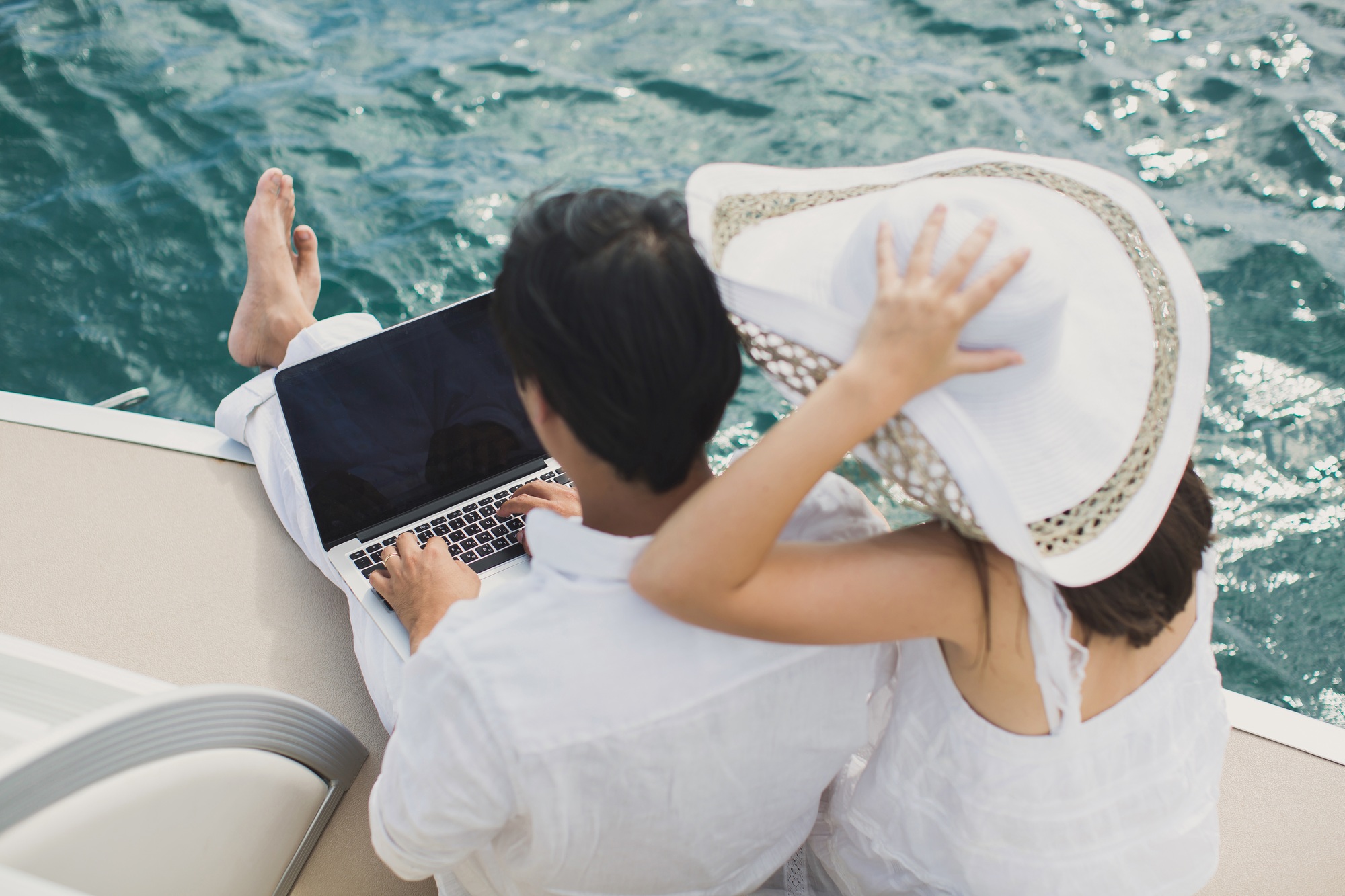 Two business people working with laptop on a sailing boat - sailing trip